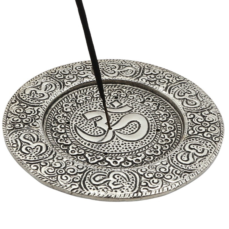 stick of incense in the centre of an aluminium incense burner with om symbol