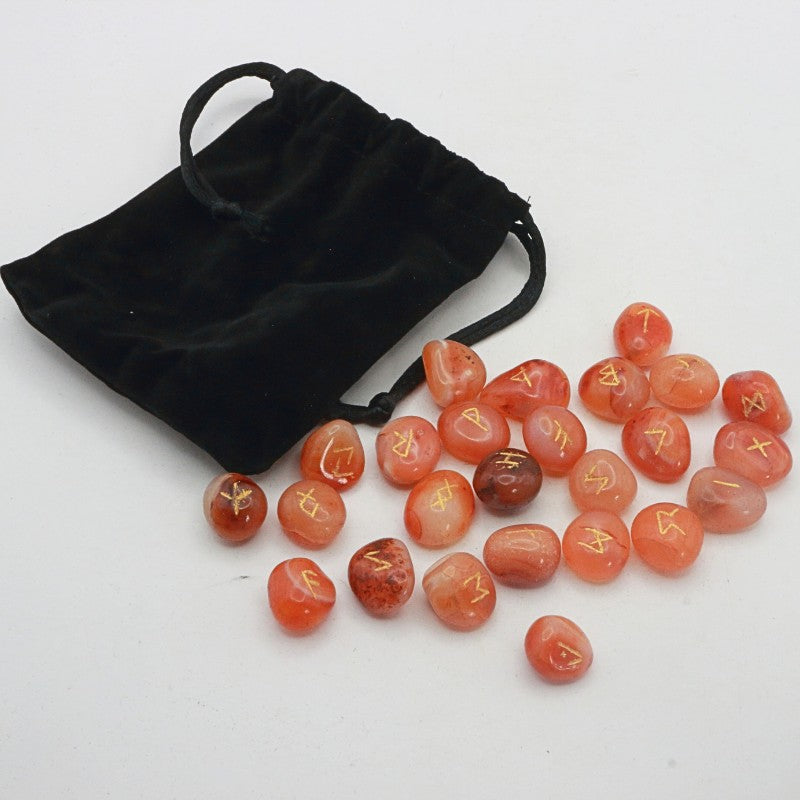 Set of orange crystal runes with rune symbols next to a black drawstring bag on a white background