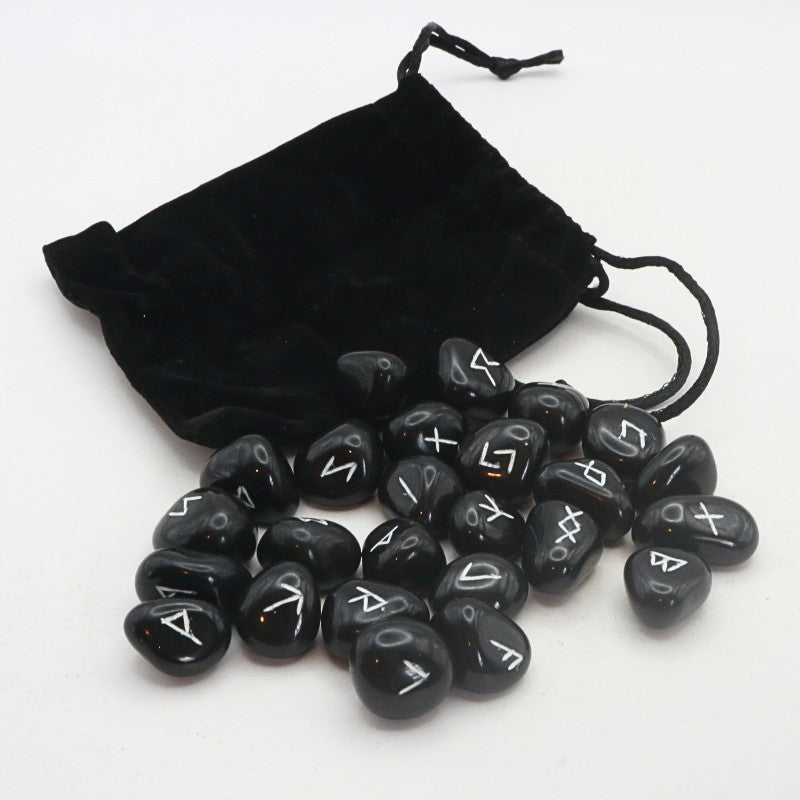 Set of black rune stones with white symbols on a white background, accompanied by a black drawstring bag.