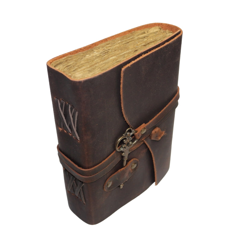 Antique style brown leather journal with a skeleton key on leather band that wraps around to close the cover. Inside contains plain "antiqued" pages Spine has laced leather across it.