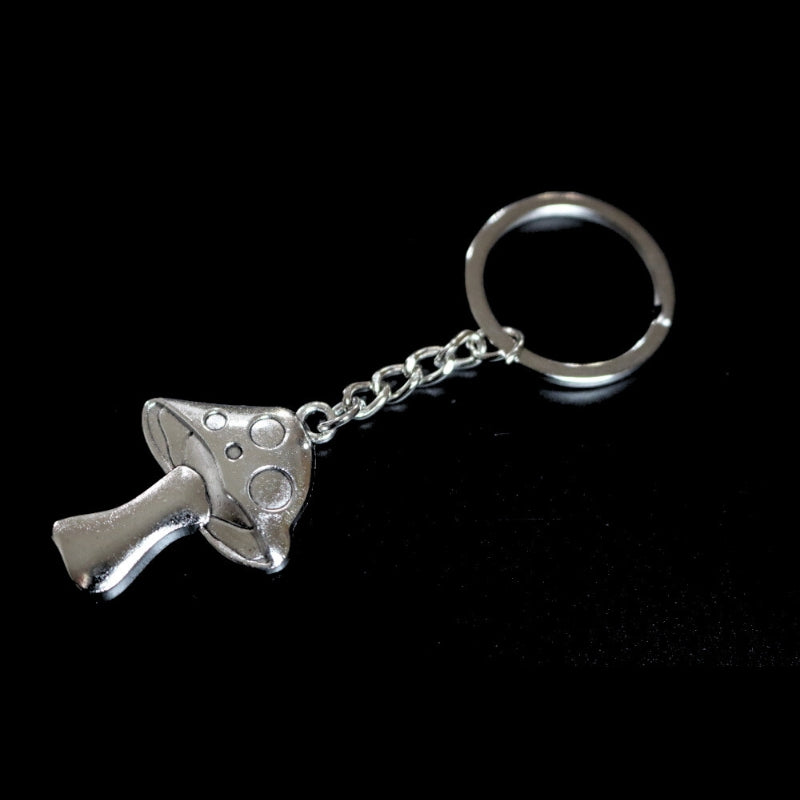 silver coloured key ring with a mushroom joined to a silver ring by a silver chain on a black background