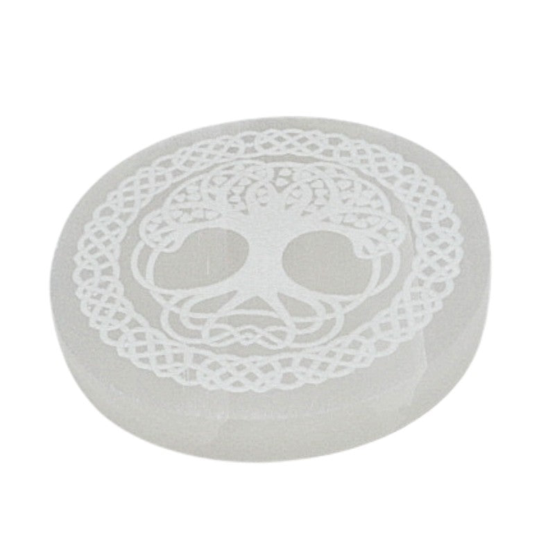 Round selenite charging stone with a tree of life design on a white background