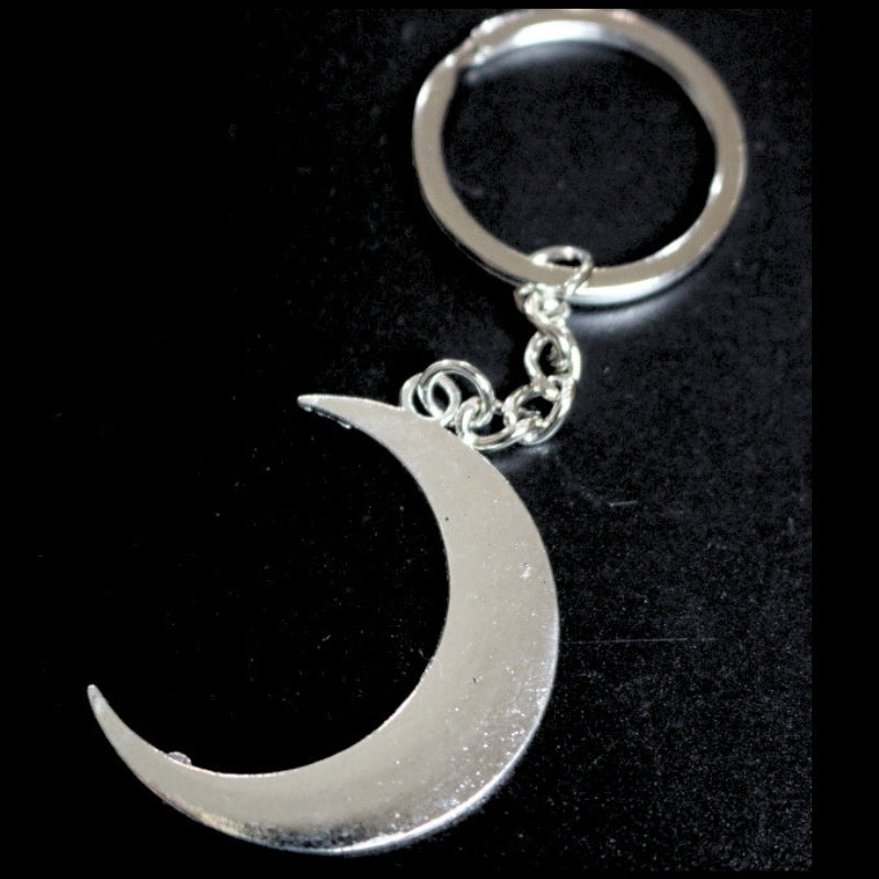 silver coloured key ring with a crescent moon joined to a silver ring by a silver chain on a black background