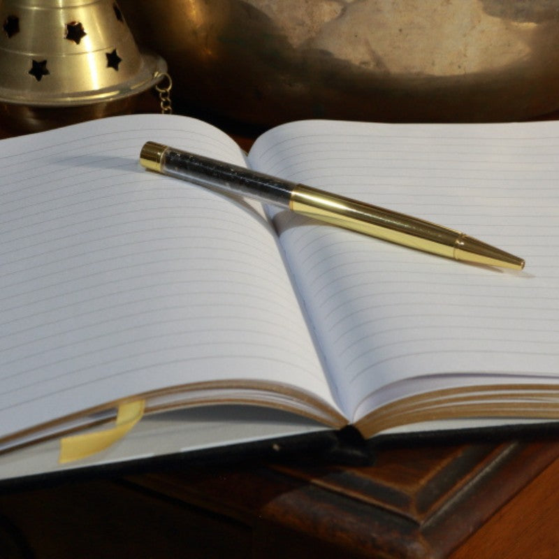 Open notebook with a gold pen on a wooden surface