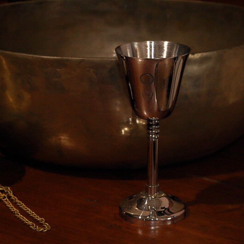 Silver coloured goblet in front of a brass singing bowl