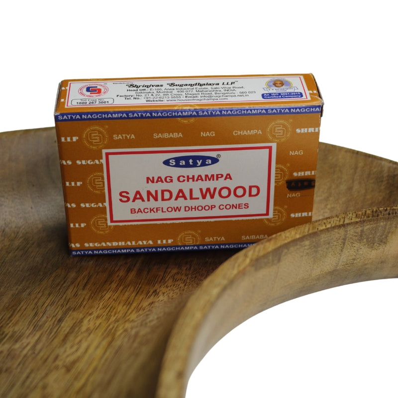 light brown box of incense cones with blue borders and a white label on the front with a red border, blue and white ellipse Satya trademark logo on the front with product name written in red sitting on a wooden crescent moon shaped dish