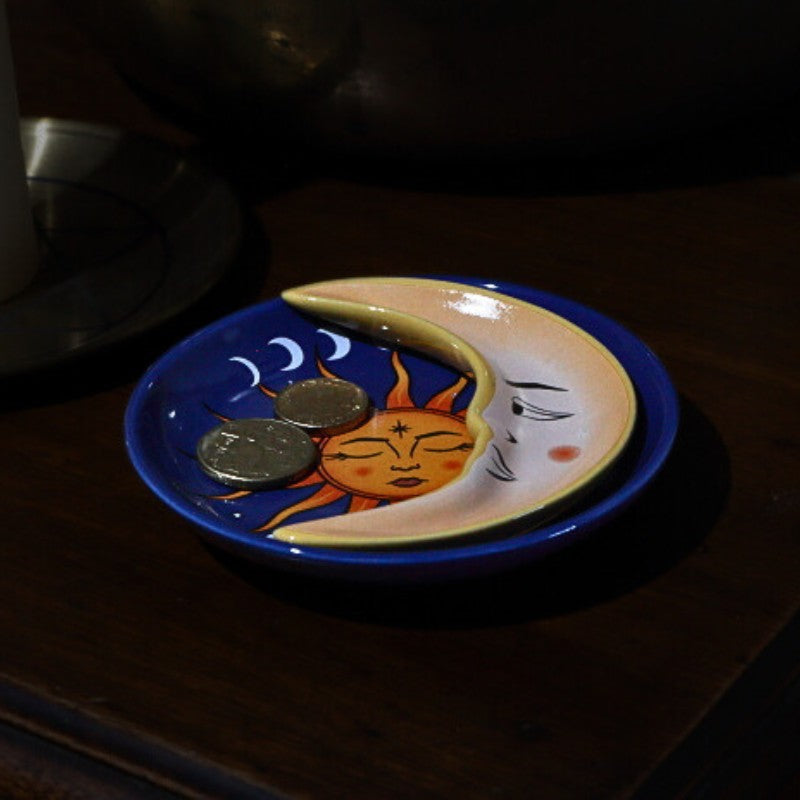 Ceramic plate with sun and moon design on a dark surface