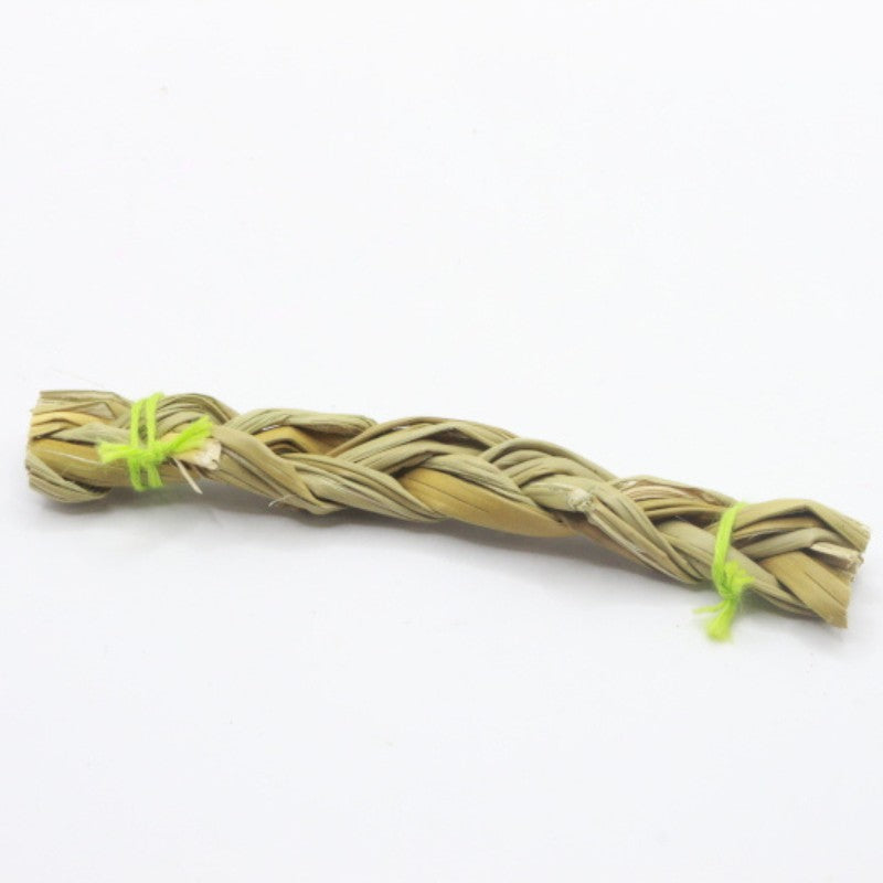 Braided sweetgrass stick with a yellow string on a white background