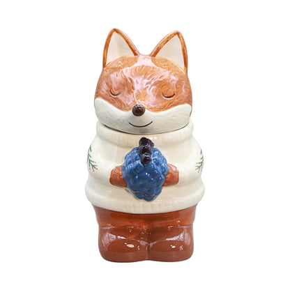 ceramic fox wearing a white jumper and holding blue berries, on a white background