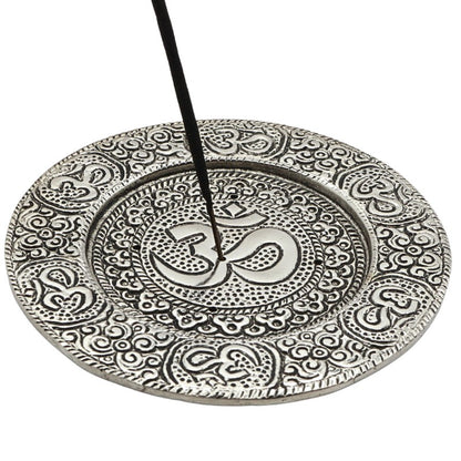 stick of incense in the centre of an  aluminium incense burner with om symbol