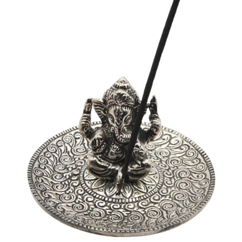 incense stick sitting in an  aluminium incense burner  with a state of ganesh in the centre