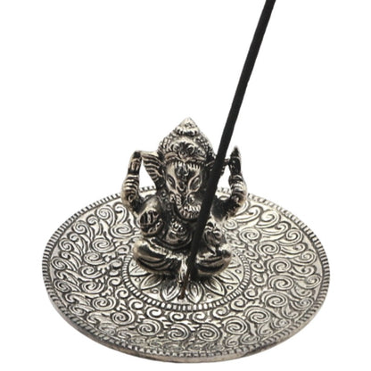 incense stick sitting in an  aluminium incense burner  with a state of ganesh in the centre