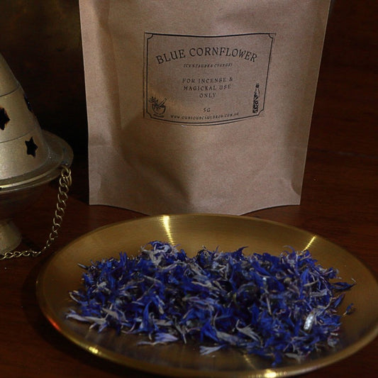 Blue cornflower on a gold plate with a brown paper bag labeled 'Blue Cornflower' in the background.
