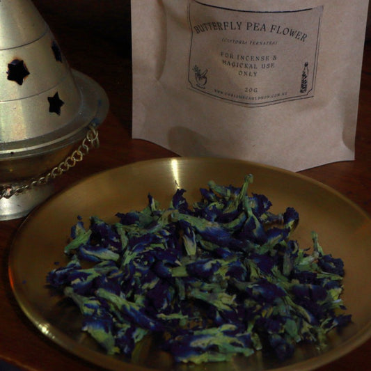 Butterfly pea flower on a gold plate with a labeled package in the background