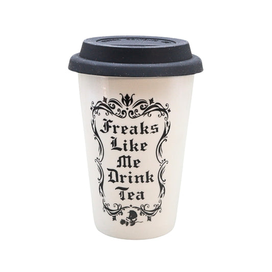 A white reusable coffee cup with a black lid, featuring the text 'Freaks Like Me Drink Tea' in a black gothic font with an ornate frame.