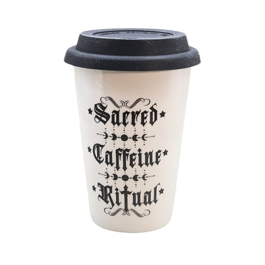 A white reusable coffee cup with a black lid, featuring the gothic-style text 'Sacred Caffeine Ritual' printed on the front.