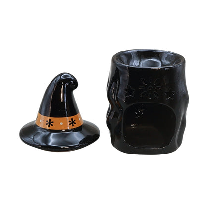 Black witch-themed ceramic candle holder set with a pointed hat-shaped lid featuring an orange band and a matching skull-shaped vessel with star and flower cutouts, shown on a white background.
