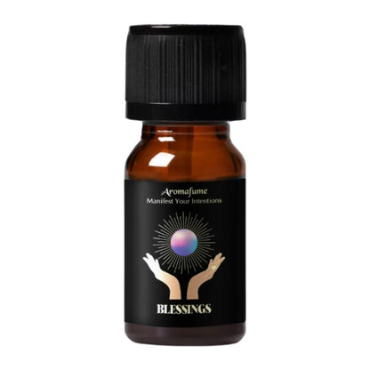 A small amber glass bottle with a black ribbed cap and a black label. The label features the brand name 'Aromafume' and the product name 'Blessings' in gold text, with a graphic of two hands holding a glowing purple orb.