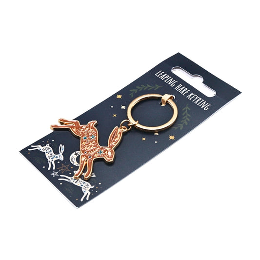 A gold-tone lapel hare keyring with a detailed hare body patterned with orange, red, and blue stones, attached to a dark blue card backing printed with 'LEAPING HARE KEYRING' and celestial illustrations.