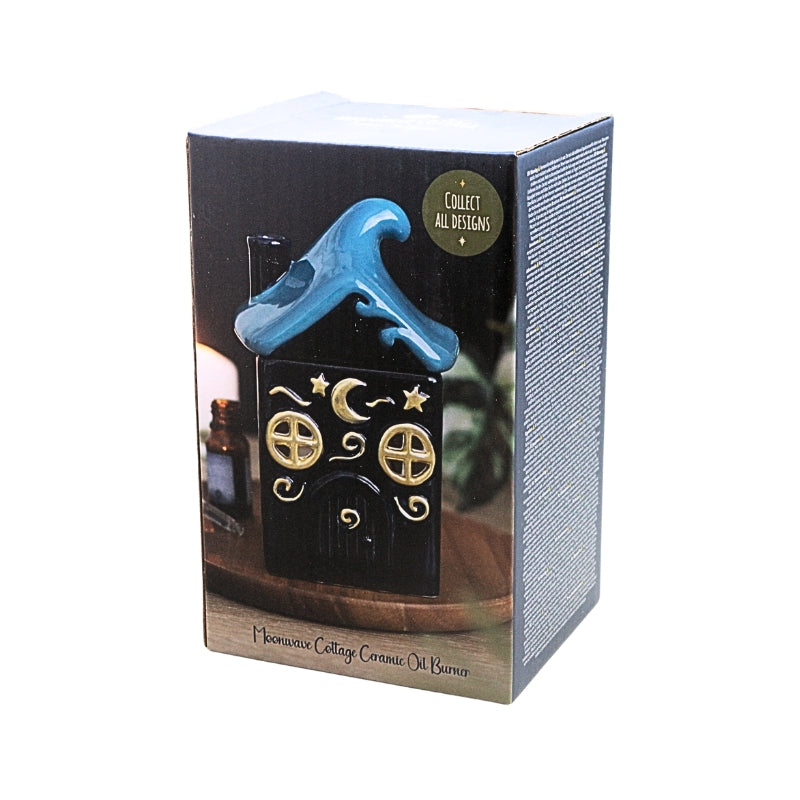 Packaged home cottage candle oil burner featuring a  dark blue house design with gold window and door details and a blue roof, shown in its retail box against a white background.