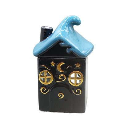A small decorative house-shaped ceramic container or ornament with a dark blue body, a light blue wave-shaped roof, and gold celestial details including stars, a crescent moon, and window motifs, shown on a plain white background