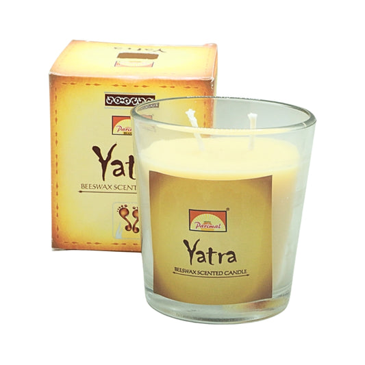 Parimal Yatra beeswax candle with two wicks in a clear glass jar, displayed in front of its gold box.
