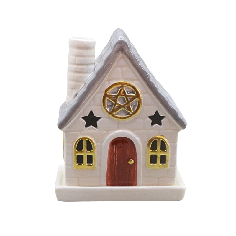 A small decorative house-shaped ceramic container or figurine with a white brick-textured body, gray roof, red-brown door, gold window trim and pentagram emblem, plus black stars, shown on a plain white background.