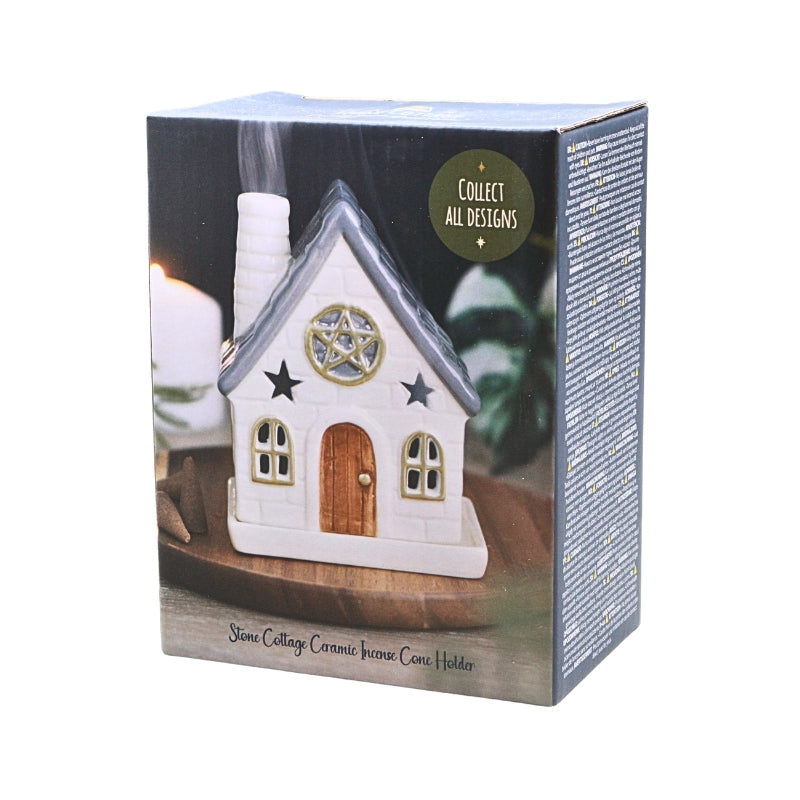 A boxed ceramic incense cone holder shaped like a small white cottage with a gray roof, brown door, and star motif on the front, shown on a plain white background.