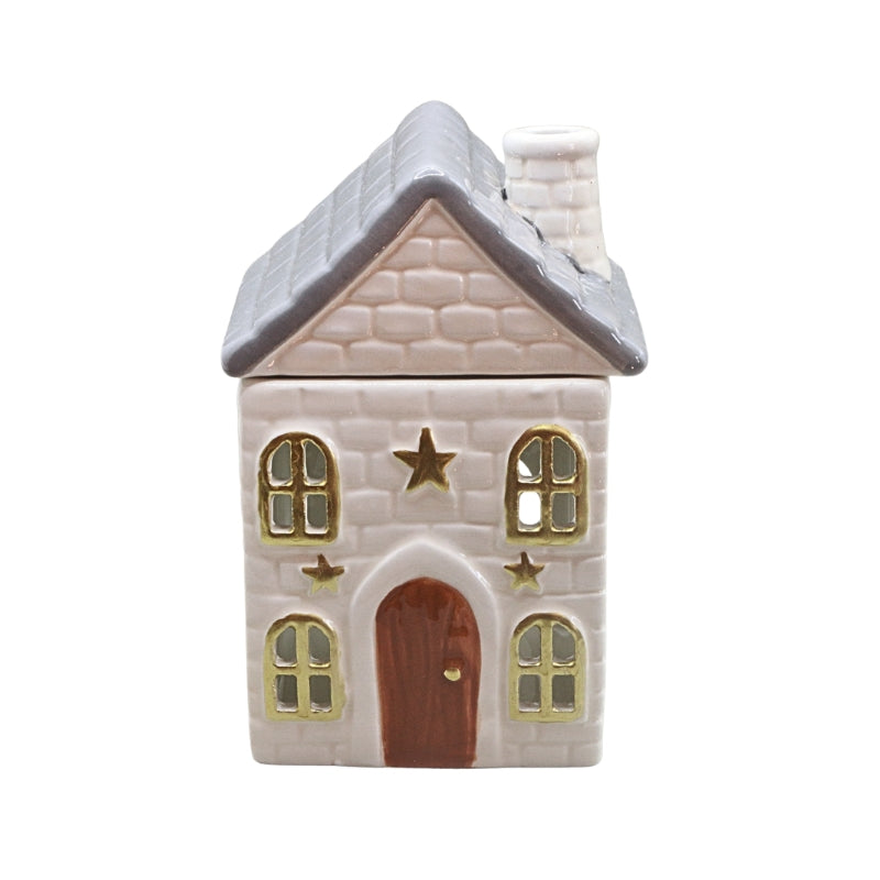 A ceramic oil burner shaped as a house ornament with a textured off-white facade, gray roof, gold-trimmed windows and stars, and a brown door, shown on a plain white background.