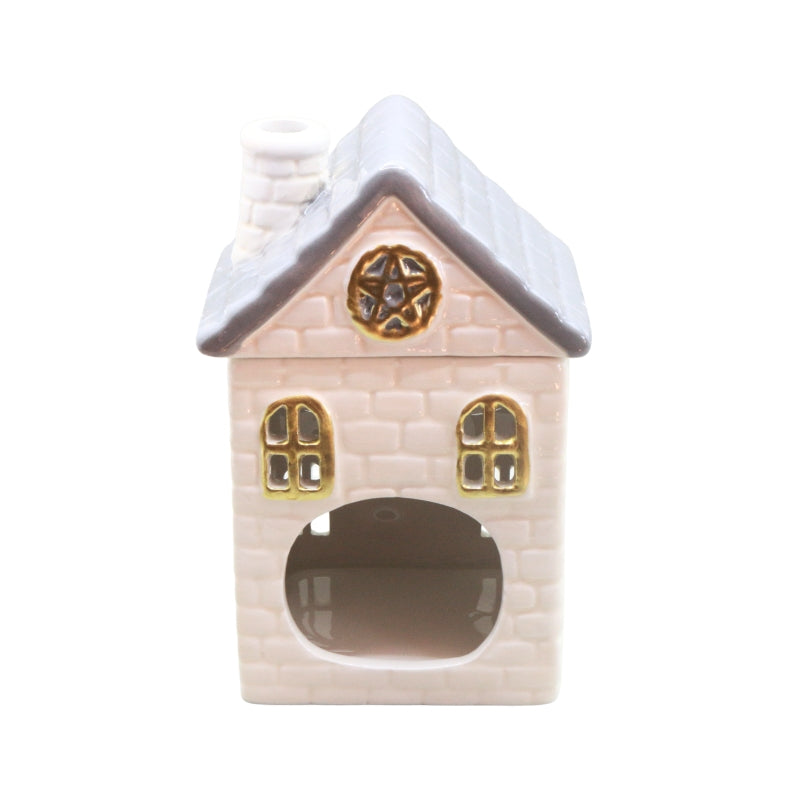 A small decorative house-shaped ceramic object with a pale cream brick-textured body, gray roof, gold window and star details, and a dark opening at the bottom, shown on a plain white background.
