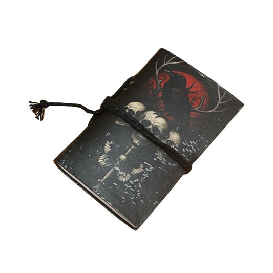 small notebook with black tie and image of a raven and skulls and red moon, on  a white background
