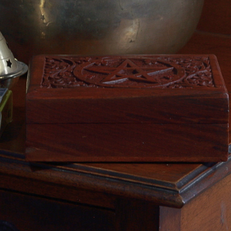 carved wooden box with pentacle design on top in front of a brass singing bowl