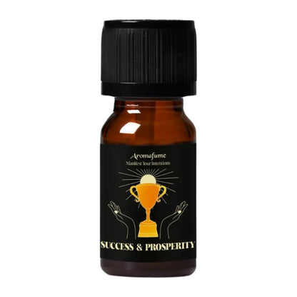 A small amber glass bottle with a black ribbed cap and a black label featuring a gold trophy graphic and the text 'Aromafume' and 'SUCCESS & PROSPERITY'.