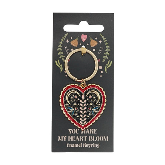 Heart-shaped enamel keyring on a black card with decorative elements