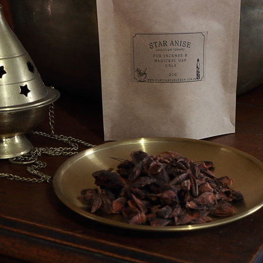 Star anise on a brass plate with a labeled brown bag in the background