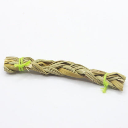 Braided sweetgrass stick with a yellow string on a white background