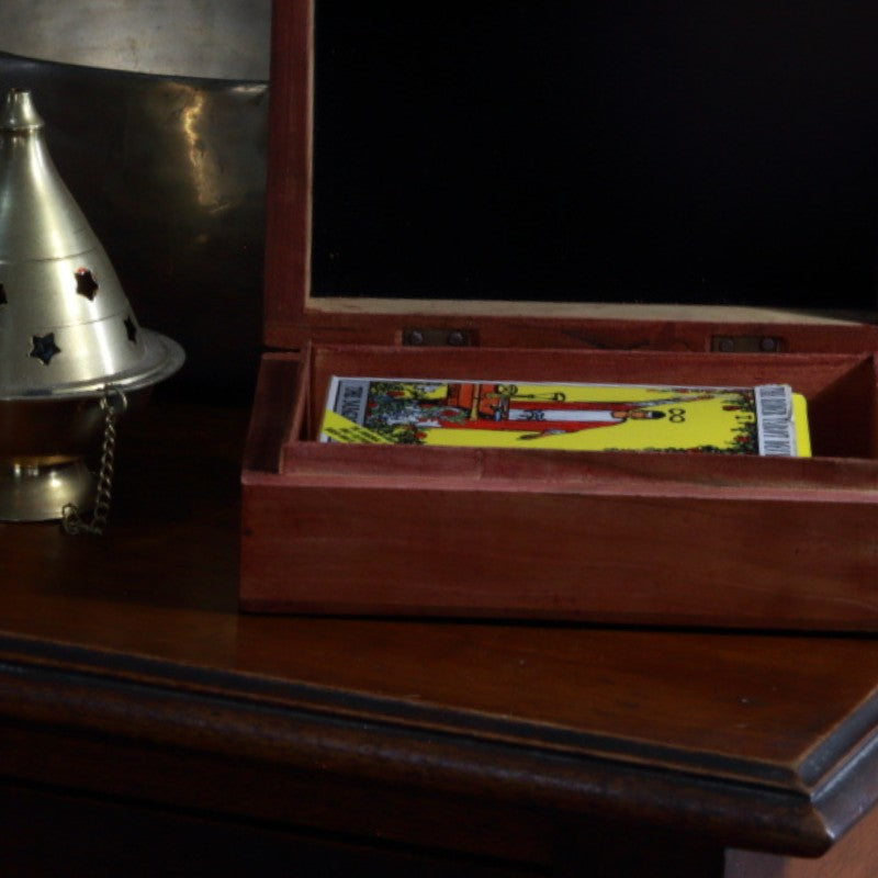 carved wooden box  sitting in front of brass singing bowl with a pack of rider waite smith tarot cards inside