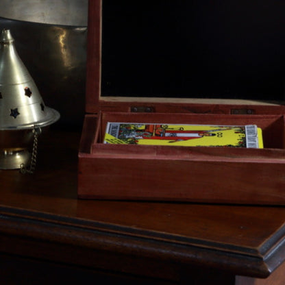 carved wooden box  sitting in front of brass singing bowl with a pack of rider waite smith tarot cards inside