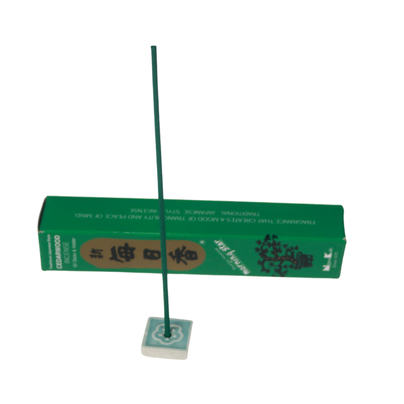 cedarwood incense in a blue and white incense tile in front of a green and gold  cedarwood incense box