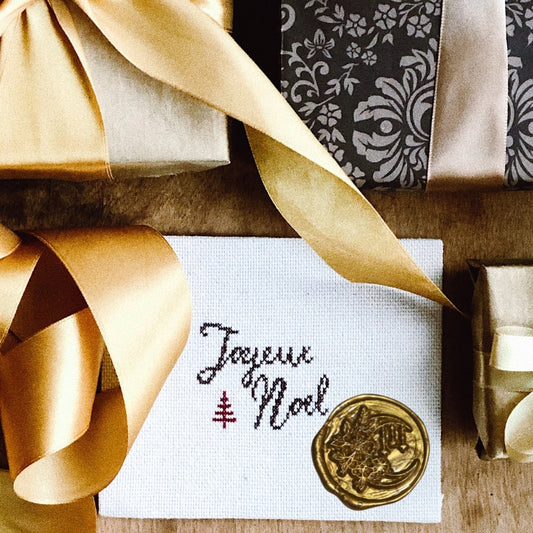 gold wax seal of a crescent moon and flowers on a tapestry , surrounded by ribbons and presents